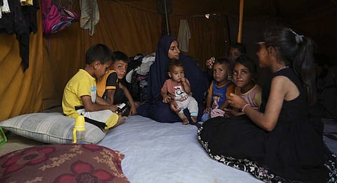 Maryam Abu Shaar, 29, sits with her children inside their tent at a camp for displaced Palestinians in Mawasi Khan Younis, Gaza Strip, on the first day of Eid al-Adha, Friday, June 6, 2025.
