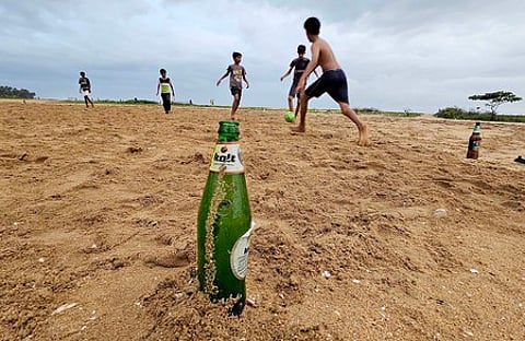 Beer bottles abandoned by anti- social people in night time at Kozhikode beach being used by children to mark football goalpost