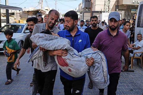 Relatives carry the body of 13-year-old Seraje Ebrahim, killed in an Israeli strike on a drinking water distribution point, for burial outside Al-Awda Hospital in Nuseirat, central Gaza Strip, Sunday, July 13, 2025.