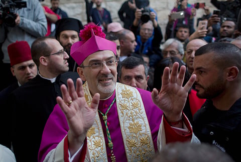 In this Dec. 24, 2018 file photo, Christians celebrate the arrival of Archbishop Pierbattista Pizzaballa, the top Roman Catholic cleric in the Holy Land, center, after he crossed an Israeli military checkpoint from Jerusalem ahead of midnight Mass at the Church of the Nativity, traditionally recognized by Christians to be the birthplace of Jesus Christ, in the West Bank city of Bethlehem