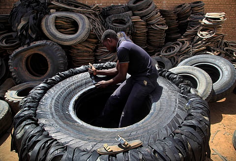 A Sudanese man cuts a heavy duty machine tire into rubber pieces at a shop in a market in Omdurman, Khartoum, Sudan