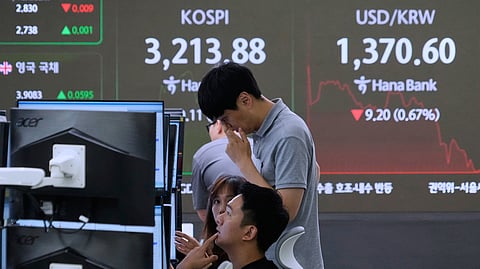Currency traders work near a screen showing the Korea Composite Stock Price Index (KOSPI) and the foreign exchange rate between U.S. dollar and South Korean won, top right, at the foreign exchange dealing room of the Hana Bank headquarters in Seoul, South Korea, Thursday, July 24, 2025.