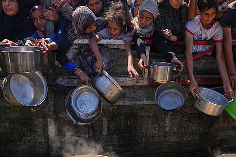 Palestinians struggle to get donated food at a community kitchen in Gaza City, northern Gaza Strip, Monday, Aug. 4, 2025.