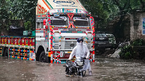 : A man pulls his two-wheeler stuck at a waterlogged road during rain at Govindpuri area, in New Delhi, Saturday, Aug. 9, 2025.