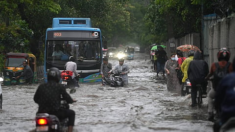 Commuters wade through a waterlogged road amid heavy rainfall, in New Delhi, Thursday, Aug. 14, 2025.
