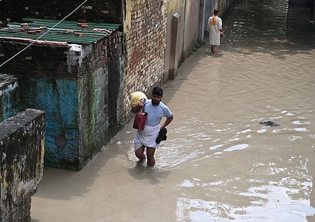 People wade through the flooded water of the Yamuna River at Yamuna Bazar in New Delhi, India, 19 August 2025.