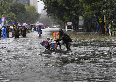 Commuters wade through a waterlogged road following heavy rainfall, in Dadar area, Mumbai, Tuesday, Aug. 19, 2025.