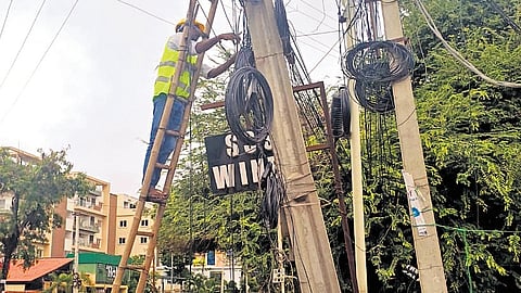 TGSPDCL employees remove unsafe cable wires from poles in Hyderabad.