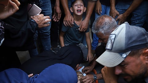 Palestinian relatives mourn over the body of 13-year-old Karim Qdeih, who was killed along with others in overnight Israeli strikes, during his funeral outside Nasser Hospital in Khan Younis, southern Gaza Strip, Saturday, Aug. 23, 2025.