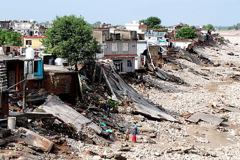 People stand near damaged houses along the banks of the Tawi river a day after it was flowing in spate due to heavy rainfall, in Jammu, Thursday, Aug. 28, 2025.
