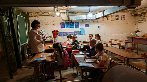 School students listen to their teacher during a lesson, in the basement of a municipal building during the first day in school in Bobryk, Sumy region, Ukraine, Monday, Sept. 1, 2025. The Bobryk school was forced to move to the basement due to endless alarms.