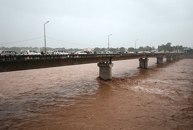 Vehicles move along a bridge over the swollen Tawi river amid rainfall, in Jammu.