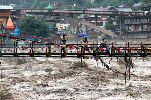 People walk along the bridge over the swollen Beas river amid rainfall, in Kullu district, Himachal Pradesh, Tuesday, Sept. 2, 2025.