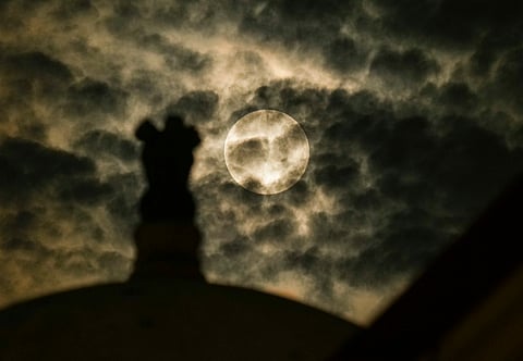 The moon rises behind an Ashok Stambh, or Pillar of Ashoka, ahead of the lunar eclipse, in New Delhi, Sunday, Sept. 7, 2025.
