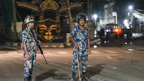 Armed Police Force personnel stand guard on a road