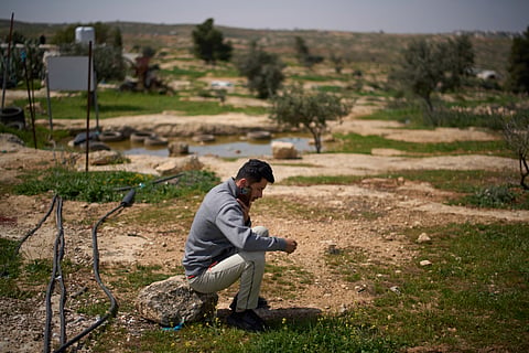 Basel Adra speaks on the phone as he sits in an area near the house of Palestinian co-director Hamdan Ballal, in Susiya in Masafer Yatta, south Hebron hills, March 25, 2025.