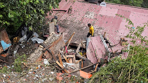 Residents inspect a house, damaged in a landslide following heavy rainfall, in Shimla, Himachal Pradesh, Tuesday, Sept. 16, 2025.
