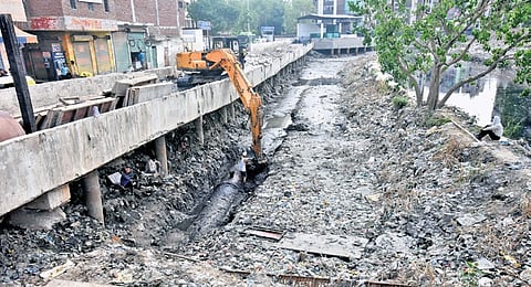 Workers cleaning drain filled with plastic and muck at Kanti Nagar in New Delhi.