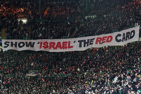 Celtic fans lift a protest banner about Israel during the Champions League playoff first leg soccer match between Glasgow Celtic and Bayern Munich at the Celtic Park Stadium in Glasgow, Scotland, Wednesday, Feb 12, 2025.