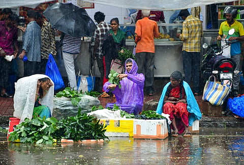 Street vendors protect themselves with plastic sheets amid rainfall, in Mumbai, Sunday, Sept. 28, 2025.