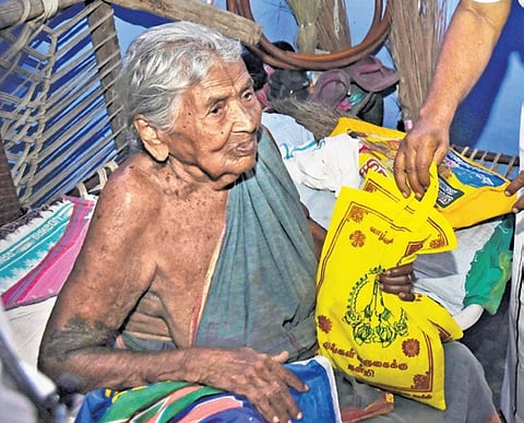 An elderly lady receives ration products under Thayumanavar scheme