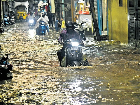 Motorists wade through a waterlogged road following heavy rain at MS Maqta in Hyderabad on Tuesday evening