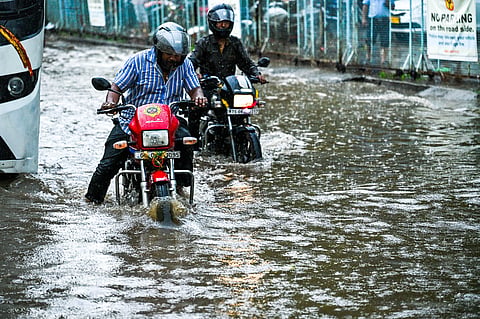 Commuters drive through flooded NH 16 service road near Iskcon Temple as heavy rain lashes in Bhubaneswar on Wednesday.