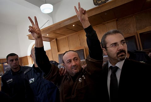Senior Fatah leader Marwan Barghouti makes the victory sign in front of the media during his arrival to testify in a trial at a Jerusalem court, Jan. 25, 2012.
