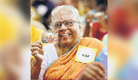 A woman beneficiary poses after receiving ATM card for Mahalir Urimai Thogai