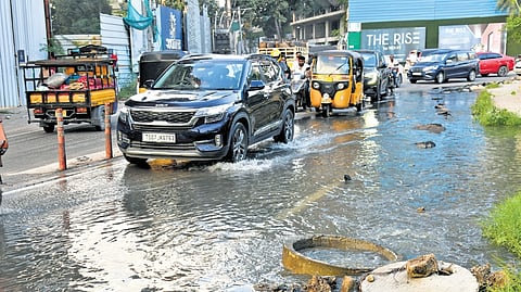Vehicles move at a snail’s pace through a waterlogged road caused by an overflowing drainage at Izzat Nagar, Kondapur