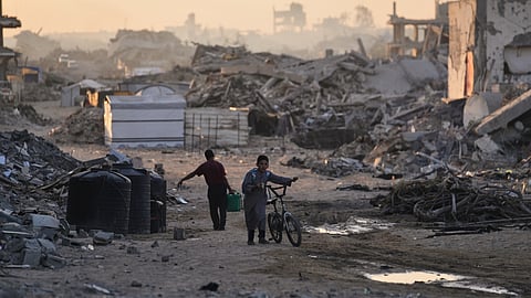 Palestinians walk through the destruction caused by the Israeli air and ground offensive in the Sheikh Radwan neighborhood in Gaza City, Wednesday, Oct. 22, 2025.