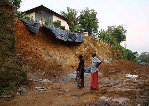 Residents point towards the sight of mudslip at Kollikkadu, Kothamangalam. A house hungs precariously over the edge of the slope where the bypass works are progressing.