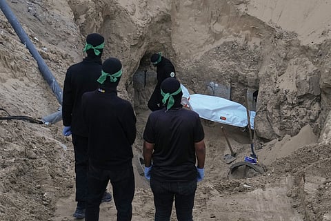 Hamas militants carry a white bag believed to contain a body, after retrieving it from a tunnel during a search for the remains of hostages in Hamad City, Khan Younis, in southern Gaza, Tuesday, Oct. 28, 2025.