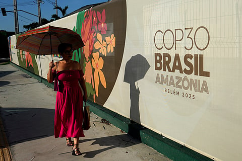 A woman walks past a sign for the COP30 U.N. Climate Summit, in Belem, Para state, Brazil, Tuesday, November 4, 2025.