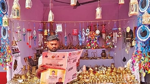 A stall owner reads The New Indian Express newspaper at Balijatra in Cuttack on Friday