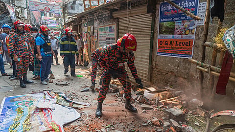A rescue official clears the debris from roof and wall collapse after an earthquake in Dhaka, Bangladesh, Friday, Nov. 21, 2025.