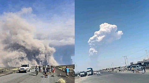In this photo released by the Afar Government Communication Bureau, people watch ash billow from an eruption of the long-dormant Hayli Gubbi Volcano in Ethiopia's Afar region, Sunday, Nov. 23, 2025.