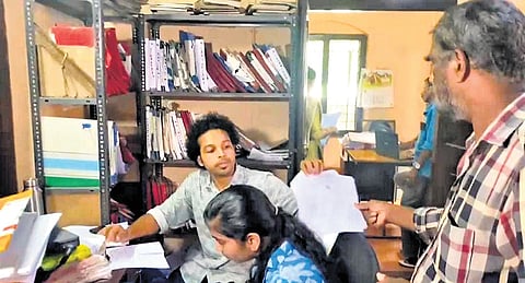 A Munambam resident handing over documents associated with the payment of land tax at Pallipuram village office on Wednesday