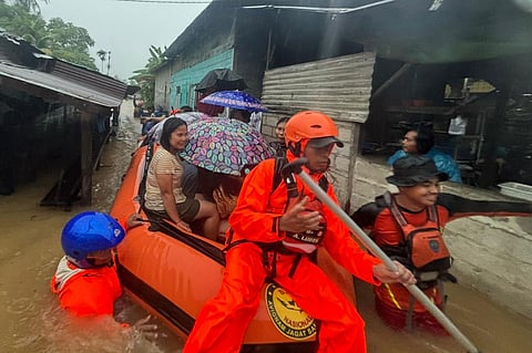 Rescuers on a rubber boat evacuate residents from their flooded home in North Sumatra province.