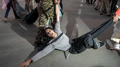 A protester being detained by security personnel during a protest against worsening air quality in the national capital, near the India Gate, in New Delhi, Sunday, Nov. 23, 2025.
