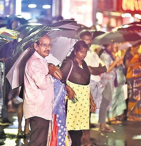 People wait for buses at Vadapalani amid the rains in Chennai