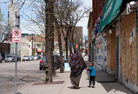 A woman and a child hold hands as they walk down a street in the predominantly Somali neighborhood of Cedar-Riverside in Minneapolis on Thursday, May 12, 2022.