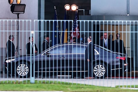 German Chancellor Friedrich Merz, right, watches Ukraine's President Volodymyr Zelenskyy arriving at the chancellory in Berlin, Germany, Sunday, Dec. 14, 2025.