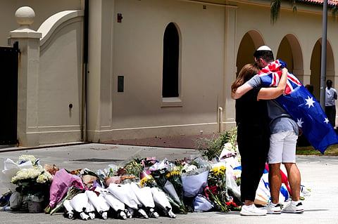A couple lay flowers at a tribute to shooting victims outside the Bondi Pavilion at Sydney's Bondi Beach, Monday, Dec. 15, 2025.