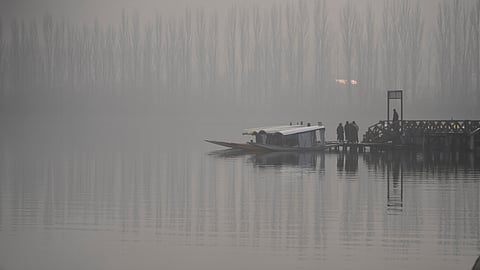 Boatmen wait for tourists near their parked boats through dense fog on a cold day at Dal Lake in Srinagar, Indian controlled Kashmir, Wednesday, Dec. 3, 2025.