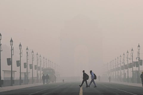 Visitors walk across the Kartavya Path near the India Gate on a smoggy winter morning, in New Delhi, Wednesday, Dec. 17, 2025.