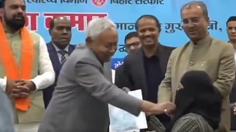 The screengrab from a viral video shows Bihar CM Nitish Kumar removing the hijab of a doctor.