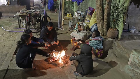 A family sitting around bonfire to beat the cold in front of their house on Monday-