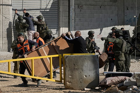 Israeli soldiers frisk a Palestinian man as residents collect their belongings ahead of planned home demolitions in the refugee camp of Nur Shams, in the West Bank city of Tulkarem, Wednesday, Dec. 17, 2025.