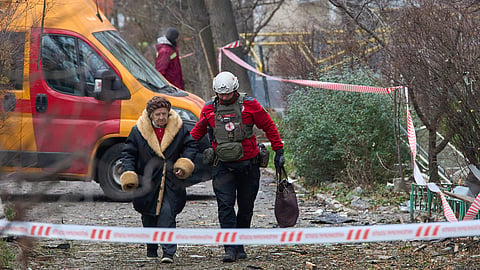 In this photo from Dec. 23, 2025, a paramedic evacuates an elderly resident after a Russian drone hit an apartment building during an aerial attack in Kyiv, Ukraine.